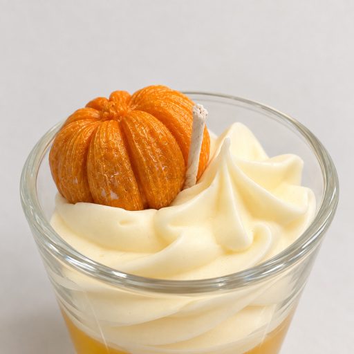 A Pumpkin Spice desszertgyertya tök alakú viaszdísze és krémszínű habrétege közelről